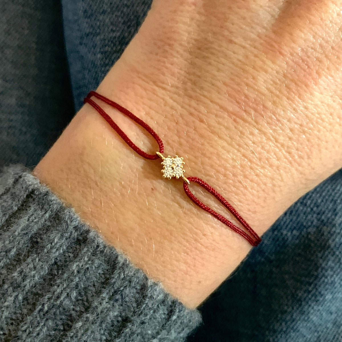 ANNA VON BERGMANN Kordelarmband GIDDY aus goldplattiertem Messing mit Zirkonia, dunkelrote Kordel am Handgelenk getragen