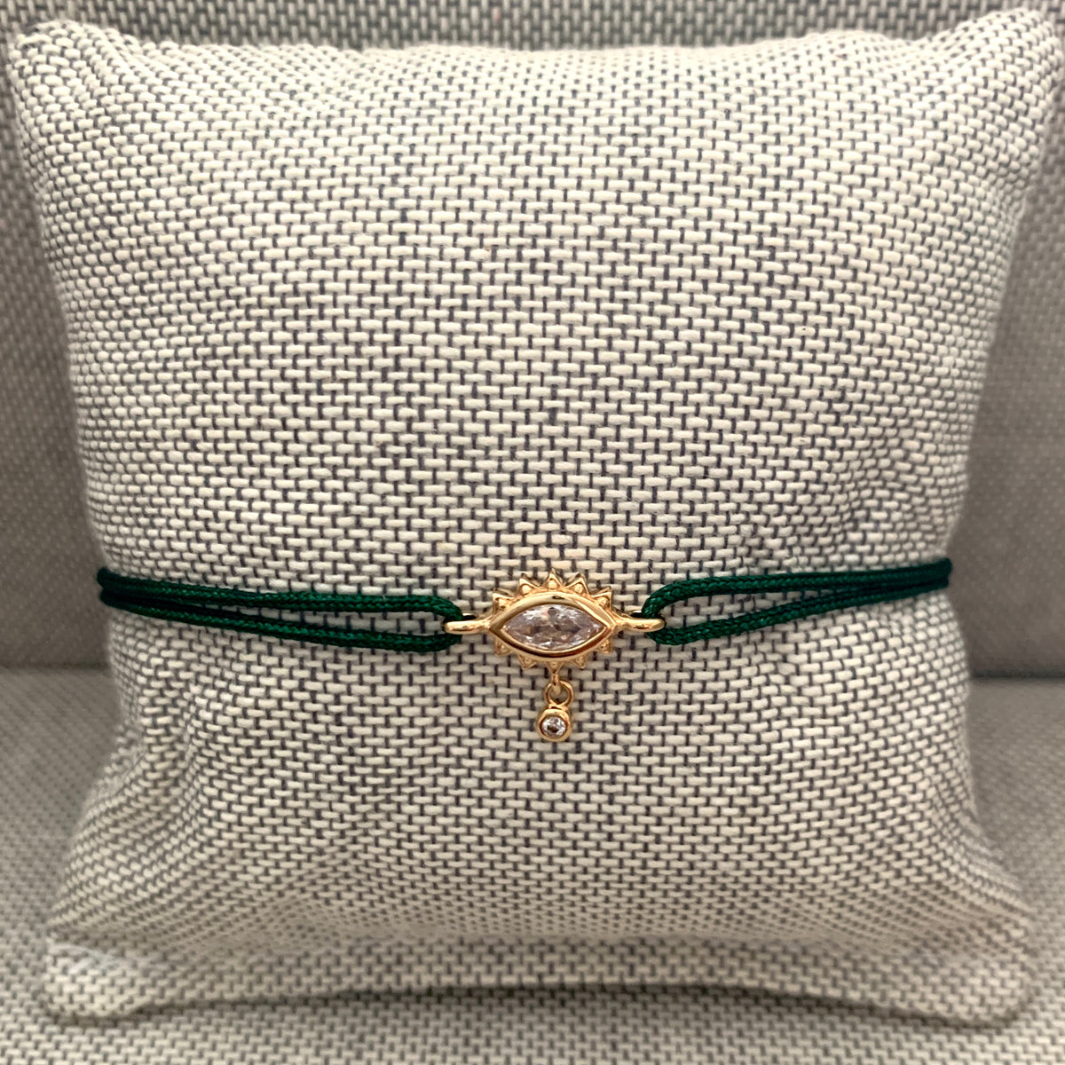 ANNA VON BERGMANN Kordelarmband GIDDY aus goldplattiertem Messing, Augenmotiv mit Zirkonia an grüner Kordel auf Kissen
