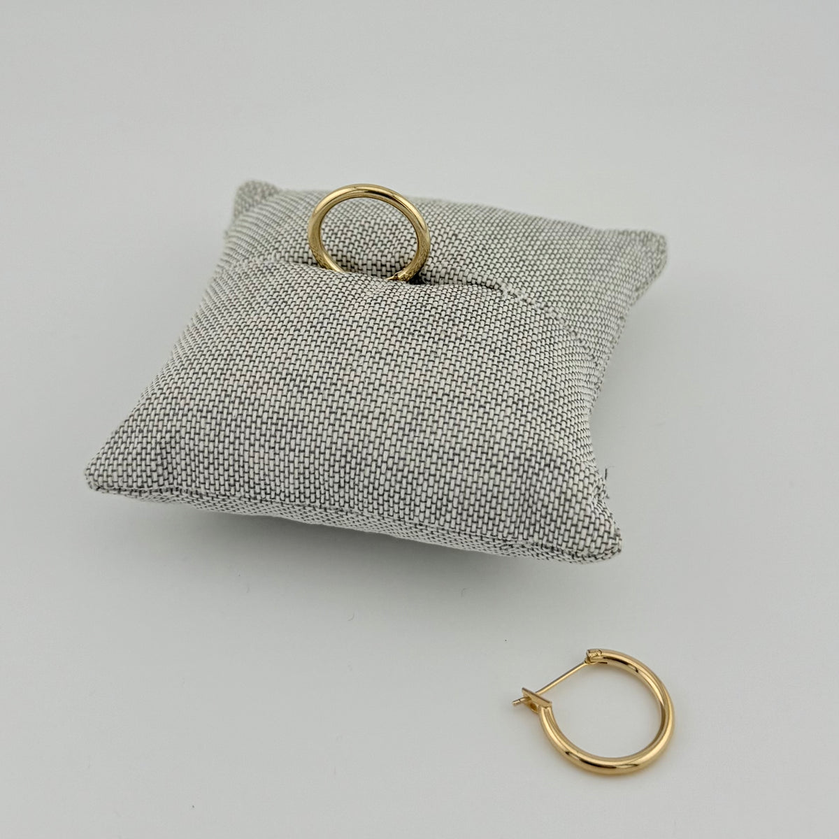 ANNA VON BERGMANN BASIS CREOLE aus 18 kt goldplattiertem Messing auf grauem Schmuckkissen und daneben liegend