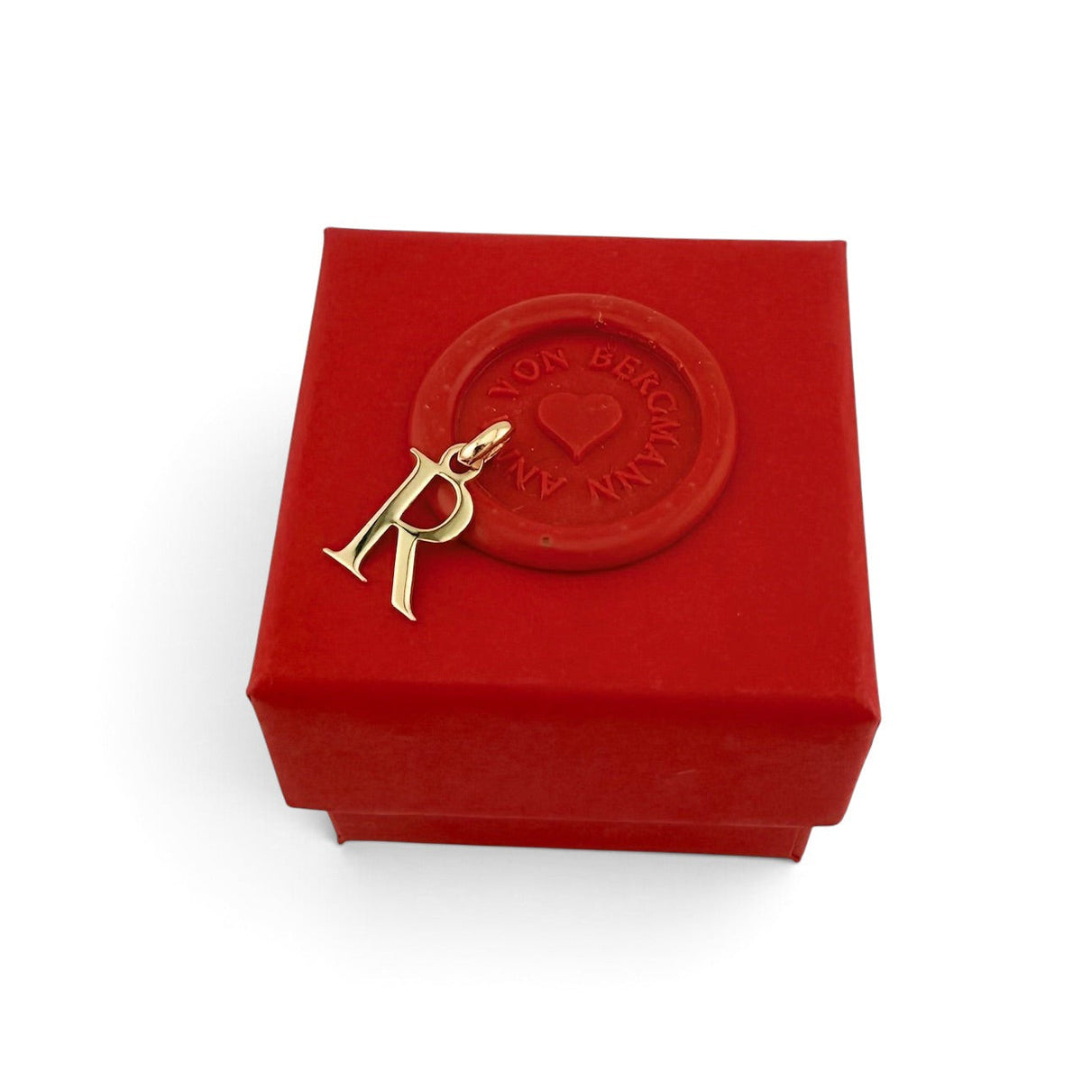 ANNA VON BERGMANN Buchstaben Anhänger R aus goldplattiertem Messing auf einer roten Geschenkbox