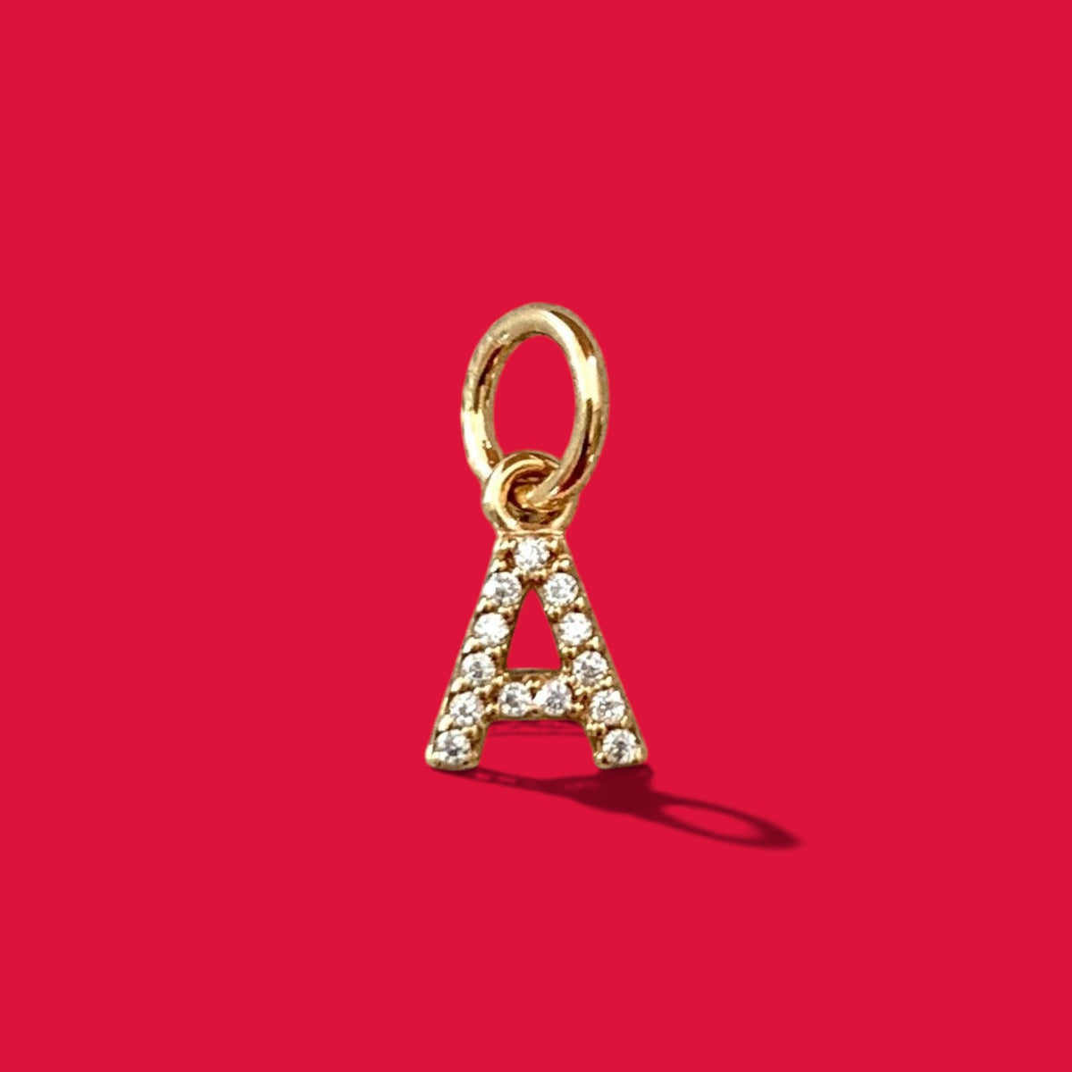 ANNA VON BERGMANN goldplattierter Buchstabenanhänger A mit Zirkonia-Steinen auf rotem Hintergrund