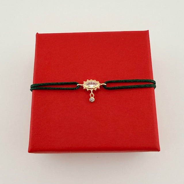 ANNA VON BERGMANN Kordelarmband GIDDY aus goldplattiertem Messing, Augenmotiv an grüner Kordel auf roter Geschenkbox