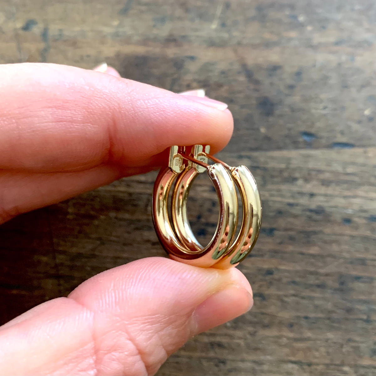 ANNA VON BERGMANN OHRCREOLEN TUBE aus 18 kt goldplattiertem Messing, zwei Creolen zwischen den Fingern gehalten