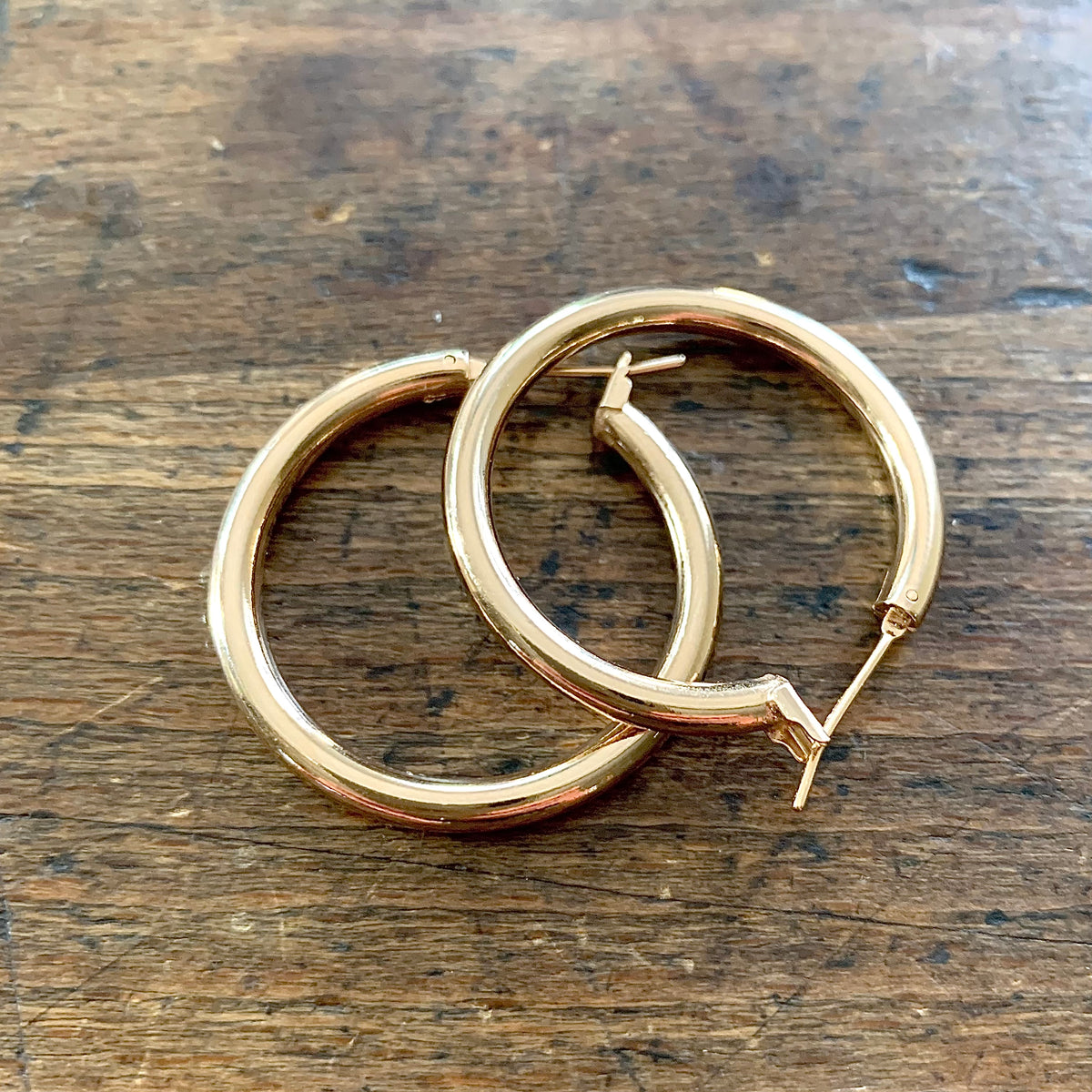 ANNA VON BERGMANN OHRCREOLEN TUBE aus 18 kt goldplattiertem Messing, Paar übereinander liegend auf Holz