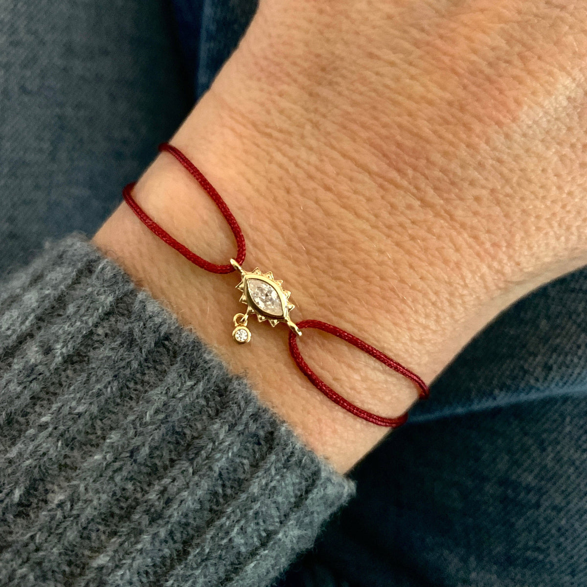 ANNA VON BERGMANN Kordelarmband GIDDY aus goldplattiertem Messing, Augenmotiv mit Zirkonia an roter Kordel am Handgelenk