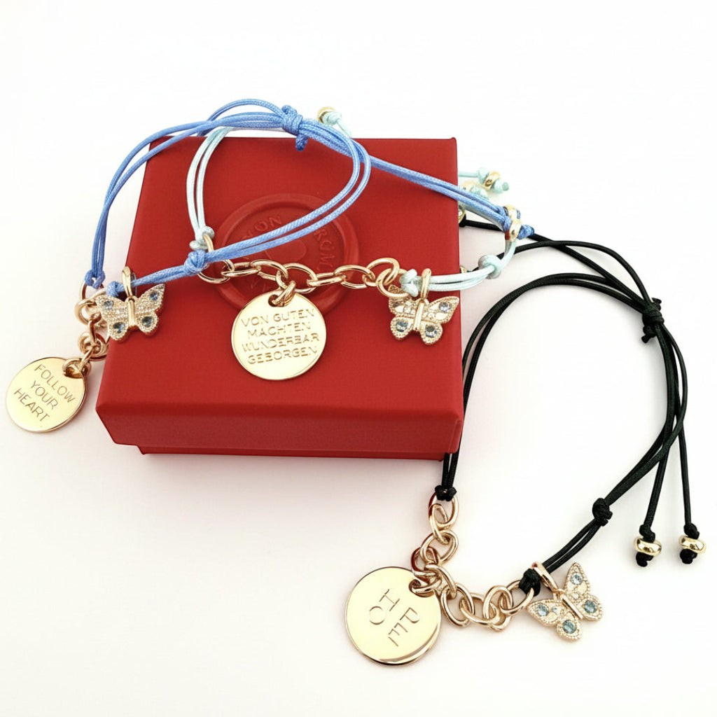 ANNA VON BERGMANN Kordelarmbänder mit goldener Gravur-Plakette und Schmetterlings-Charm mit Zirkonia in Blau und Schwarz