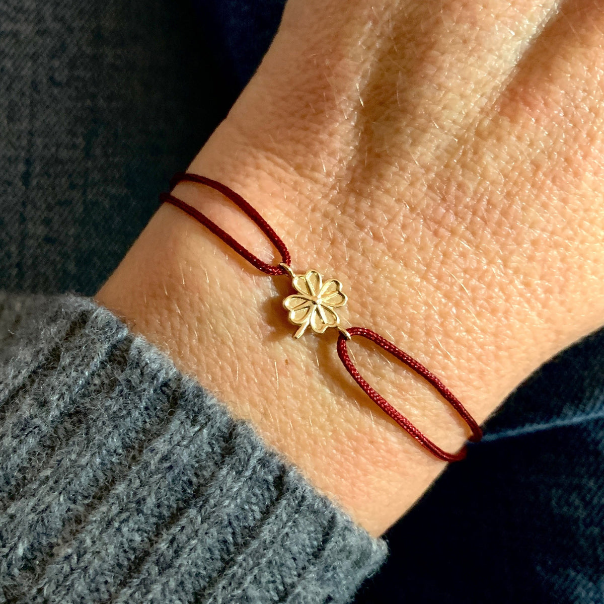 ANNA VON BERGMANN Kordelarmband GIDDY aus goldplattiertem Messing mit Kleeblatt, dunkelrote Kordel am Handgelenk