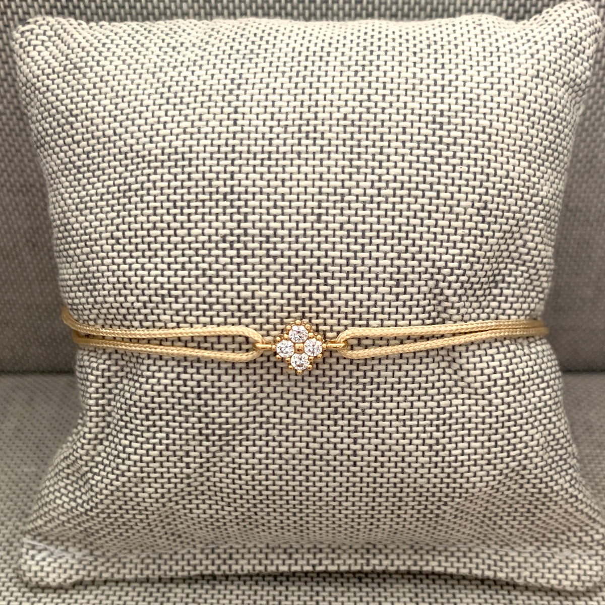 ANNA VON BERGMANN Kordelarmband GIDDY aus goldplattiertem Messing mit Zirkonia-Blüte, beige Kordel auf Kissen