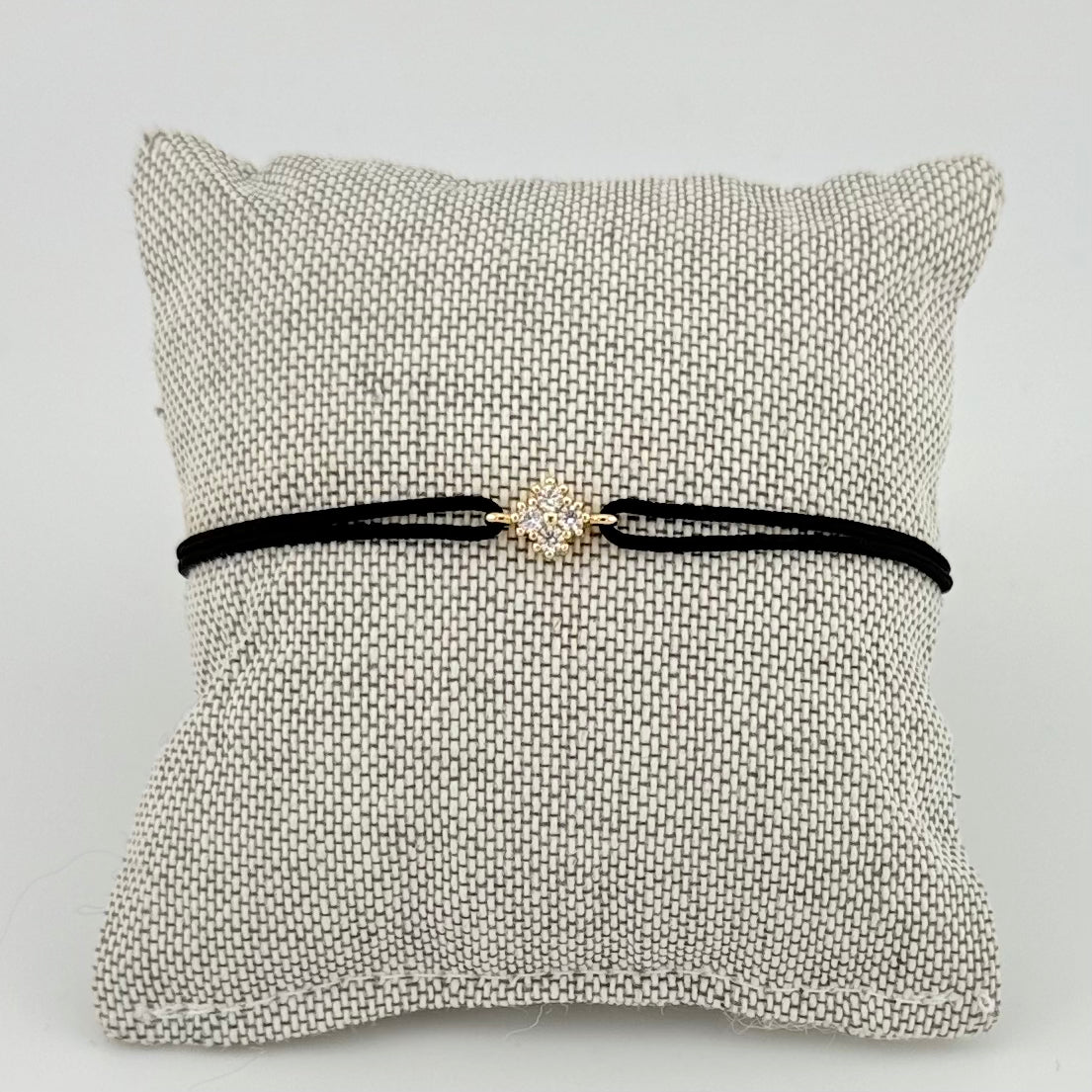 ANNA VON BERGMANN Kordelarmband GIDDY aus goldplattiertem Messing, Motiv mit Zirkonia an schwarzer Kordel auf Kissen