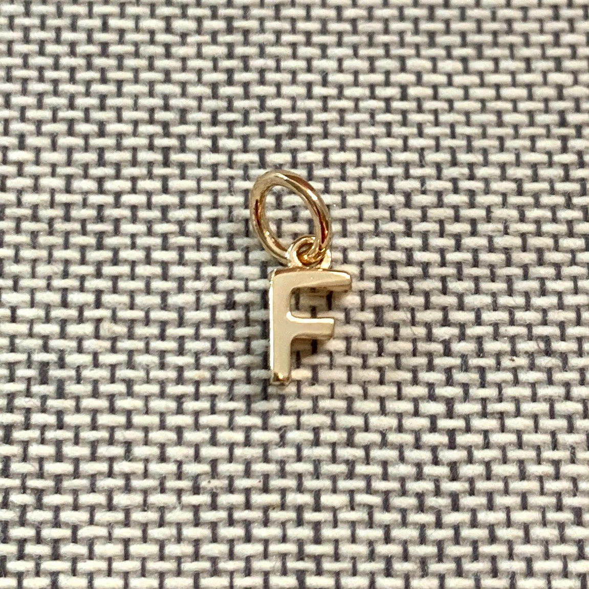 ANNA VON BERGMANN Buchstabenanhänger PETITE LETTRE aus 18 kt goldplattiertem Messing, Buchstabe F auf grauem Stoff