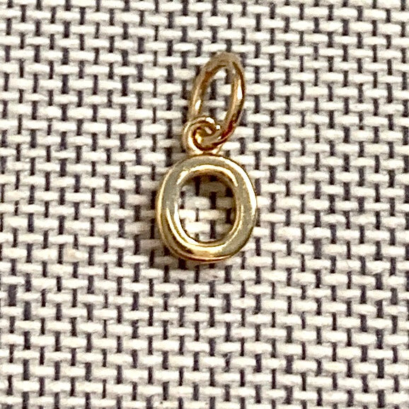 ANNA VON BERGMANN Buchstabenanhänger PETITE LETTRE aus 18 kt goldplattiertem Messing, Buchstabe O auf grauem Stoff