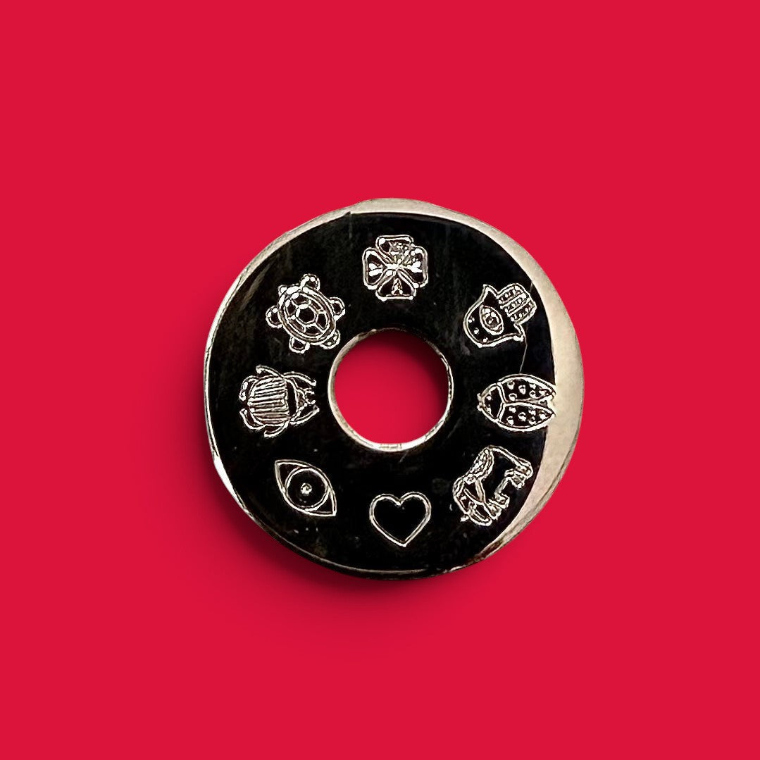 ANNA VON BERGMANN Donut Talisman Anhänger aus Sterlingsilber mit eingravierten Glückssymbolen auf rotem Hintergrund