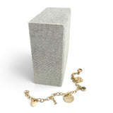 ANNA VON BERGMANN Good Luck Armband aus 18 Karat goldplattiertem Messing mit fünf Anhängern vor einer grauen Box