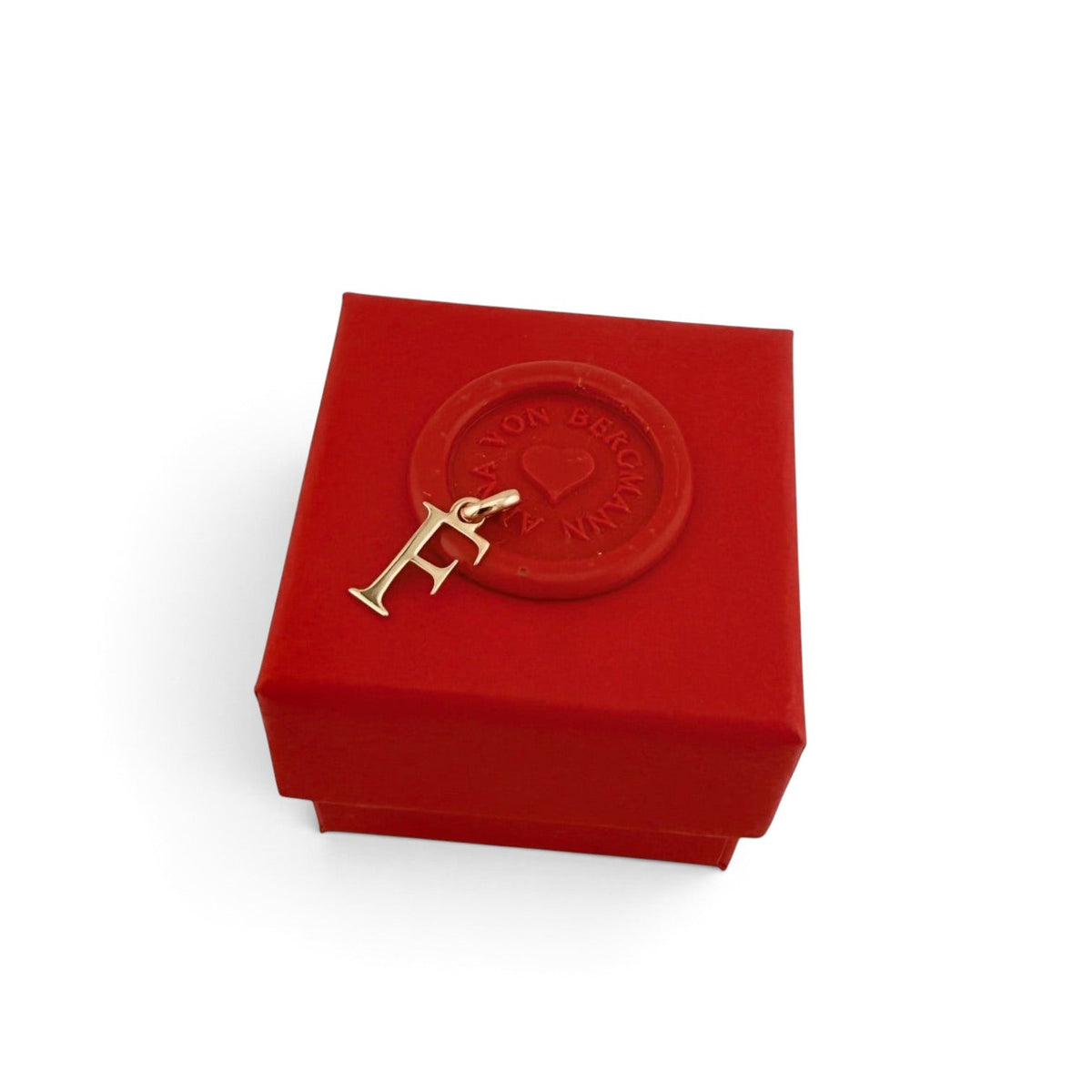 ANNA VON BERGMANN goldplattierter Buchstaben-Anhänger F auf einer roten Geschenkbox mit Siegel