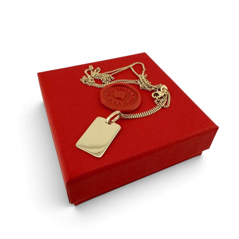 ANNA VON BERGMANN goldplattierte Kette mit rechteckigem Dog Tag Anhänger auf einer roten Geschenkbox