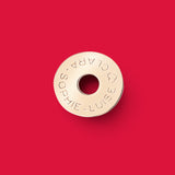 ANNA VON BERGMANN Donut Anhänger aus goldplattiertem Messing mit individueller Gravur auf rotem Hintergrund