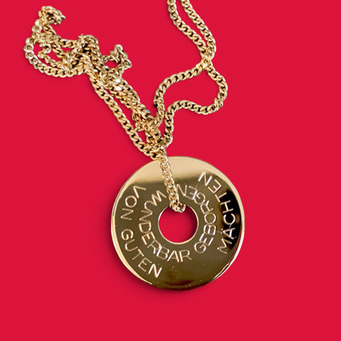 ANNA VON BERGMANN Donut-Kette aus goldplattiertem Messing mit individueller Gravur auf rotem Hintergrund