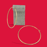 ANNA VON BERGMANN Hula Hoop Creolen aus 18k goldplattiertem Messing mit 70 mm Durchmesser vor einem Leinenetui