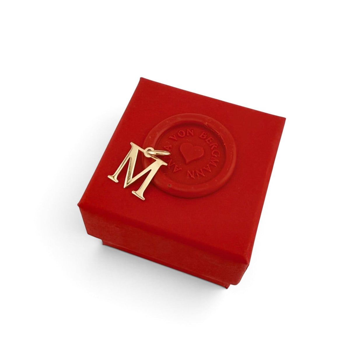 ANNA VON BERGMANN goldener Buchstabenanhänger M aus vergoldetem Messing auf einer roten Geschenkbox