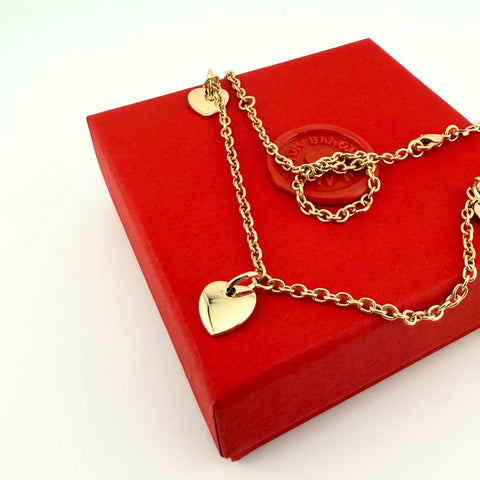 Personalisierte Gravurkette Family Mini mit goldenen Herzanhängern aus recyceltem Edelmetall auf roter Geschenkbox – Anna von Bergmann München