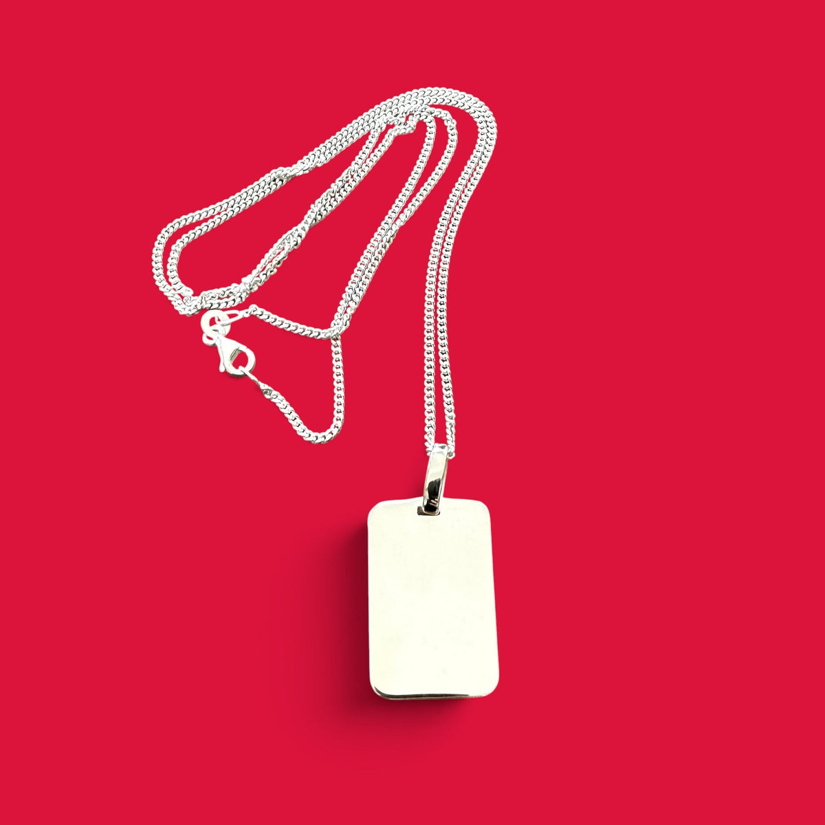 ANNA VON BERGMANN Kette mit rechteckigem Dog Tag Anhänger aus glänzendem Sterlingsilber auf rotem Hintergrund