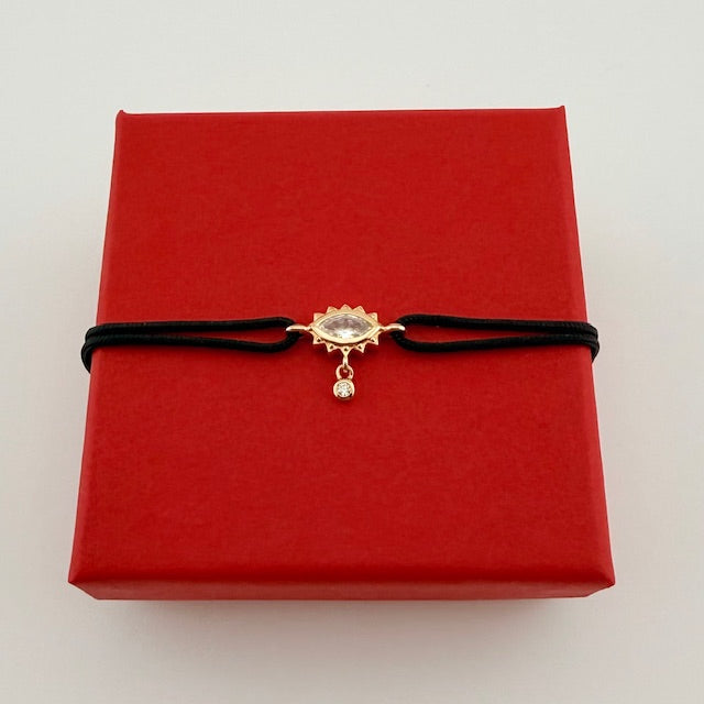 ANNA VON BERGMANN Kordelarmband GIDDY aus goldplattiertem Messing mit Augenmotiv, schwarze Kordel auf roter Box