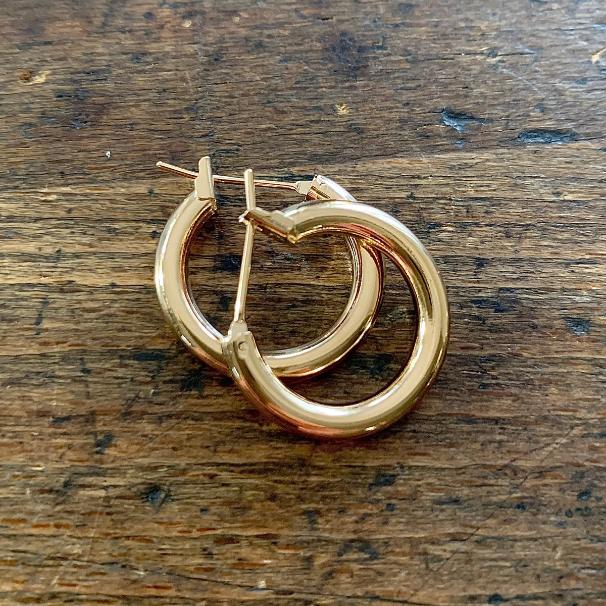 ANNA VON BERGMANN OHRCREOLEN TUBE aus 18 kt goldplattiertem Messing, Paar auf dunklem Holz